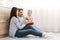 Millennial parents playing with baby son on kitchen floor