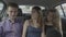 Millennial passengers friends talking and telling stories during traveling uber car on urban road -