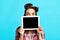 Millennial pinup lady hiding behind tablet with blank screen, offering space for website or application, blue background