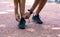 Millennial sportsman tying laces of his shoes on jogging track, closeup of legs