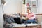 Millennial teen girl sit at couch in living room study on laptop making notes