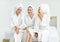 Millennial three Asian female customers friends in white clean bathrobes and towels have appointment at massage resort sitting on