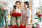 Millennial two Asian young professional female flower shopkeeper owner decorator wearing apron standing smiling using smartphone