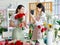 Millennial two Asian young professional female flower shopkeeper owner decorator wearing apron standing smiling using smartphone