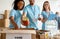 Millennial volunteers putting jars in box while sorting donated food, working in community charity donation center