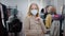 Millennial woman in face medical mask in shopping mall chooses autumn jacket coat new outfit trying posing looking at
