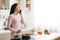 Millennial woman talking on phone, preparing lunch at kitchen