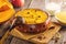 Millet porridge with pumpkin and raisins baked in a clay bowl on wooden background.