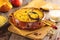 Millet porridge with pumpkin and raisins baked in a clay bowl on wooden background.