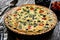 Millet quiche with spinach, black olives, cherry tomatoes and ricotta on wooden table