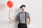 Mime holding a red balloon and leaning against wall