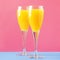 Mimosa alcohol cocktail with orange juice and dry champagne or sparkling wine in glasses, blue pink background, copy space