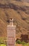  minaret tower against rugged mountain wall in atlas mountains - Morocco