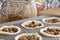 Mince pies in a baking tray with mincemeat in a clip glass jar and a spoon.  On a wood worktop