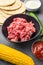Minced meat for mexican cusine with ingredients in black bowl, over grey textured background, side view