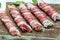 Minced meat wrapped in bacon on cast iron plate. chevapchichi or Kofta kebab. raw sausages of ground beef or pork with onions and