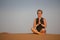 Mindfulness. A woman meditates in sand dunes during sunset.