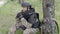 Mine clearance. Soldier with mine detector and backpack sits exhausted by a tree after heavy demining