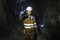 Miner in the mine. Well-uniformed miner inside mine raising thumb