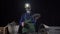 A miner wearing a dust mask and helmet with a flashlight holds a lump of black coal in his hands