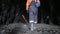 A miner wearing a helmet walks through an underground mine