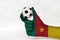 Mini ball of football in Cameroon flag painted hand on white background.