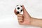 Mini ball of football in hand, hold it with two finger on white background.