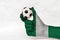 Mini ball of football in Nigeria flag painted hand, hold it with two finger on white background.