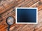 Mini blackboard and magnifier over wooden background