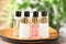 Mini bottles with cosmetic products on tray against blurred background, closeup.