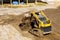 Mini bulldozer working with earth soil while doing landscaping works on construction