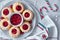 Mini bundt ring cakes with red whortleberry jam on light textured background with towel and stripy candy canes