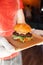 Mini burger on a stand close-up. Children fast food in a restaurant or cafe. Macro photo of burger ingredients with meat and