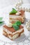 Mini cakes tiramisu with white chocolate, cocoa and candies on light background close up. Delicious dessert and candy bar.