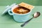 Mini casserole of minestrone soup with cracker. Direct view