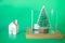 Mini Christmas tree in box and miniature home on green background. Winter holiday seasonal