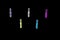 Mini colorful clothespins, arranged in staggered rows, on a black background