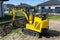 Mini digger digging a hole in the garden along the fence to the drainage pipes.