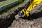 Mini digger digging a hole in the garden along the fence to the drainage pipes.