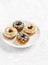 Mini donuts with lemon and chocolate icing on a white plate on bright tablecloths.