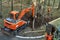 Mini excavator digging a trench among the trees for repairing city communications