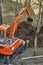Mini excavator digging a trench among the trees for repairing city communications