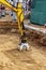 A mini excavator rams the ground with a vibrating plate. Laying of underground sewer pipes and communications during construction