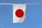 Mini fabric rail flag of Japan, it is a rectangular white banner bearing a crimson-red disc at its center.