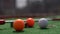 Mini-golf clubs and balls of different colors laid on artificial grass.