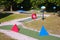 Mini golf, crazy golf course play with red and blue obstacles on a sunny day