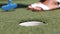 Mini golf, miniature golf or Mini Putt - woman putting with club ball in hole