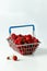 Mini grocery shopping basket with fresh raspberries on a grey background. Food photo