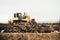 Mini industrial bulldozer moving dirt and earth with scoop. Industrial details of landscaping