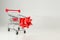 Mini iron shopping cart with Christmas red bow. Concept of sales.
